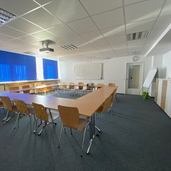 Großer Seminarraum mit Tischen und Stühlen für eine Konferenz oder Schulung.