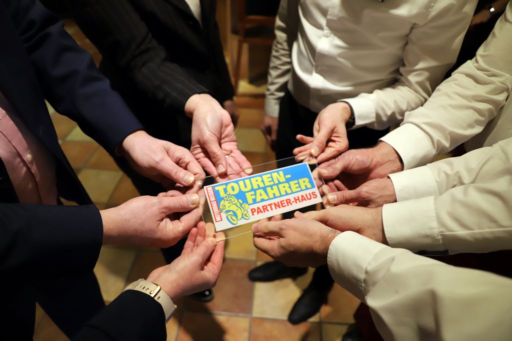 InHotel-Mitarbeiter halten die Auszeichnungsplakette Partnerhaus des Fachmagazins Tourenfahrer.