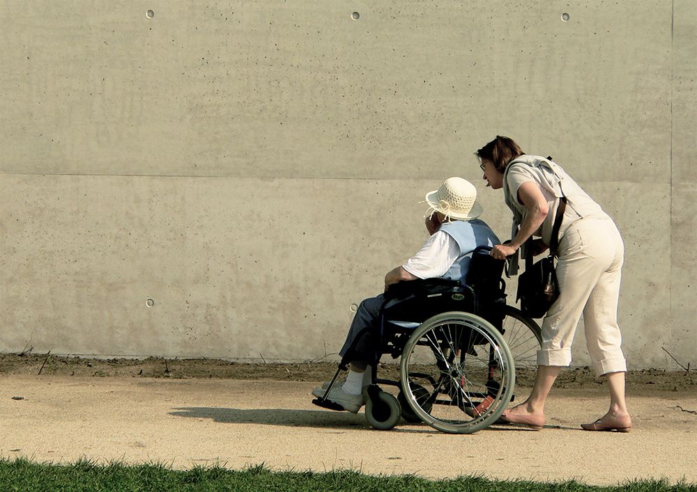 Ehrenamtliche schiebt Rollstuhl Ehrenamtliche schiebt Rollstuhl